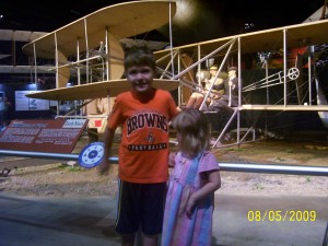 a boy and girl standing next to an airplane